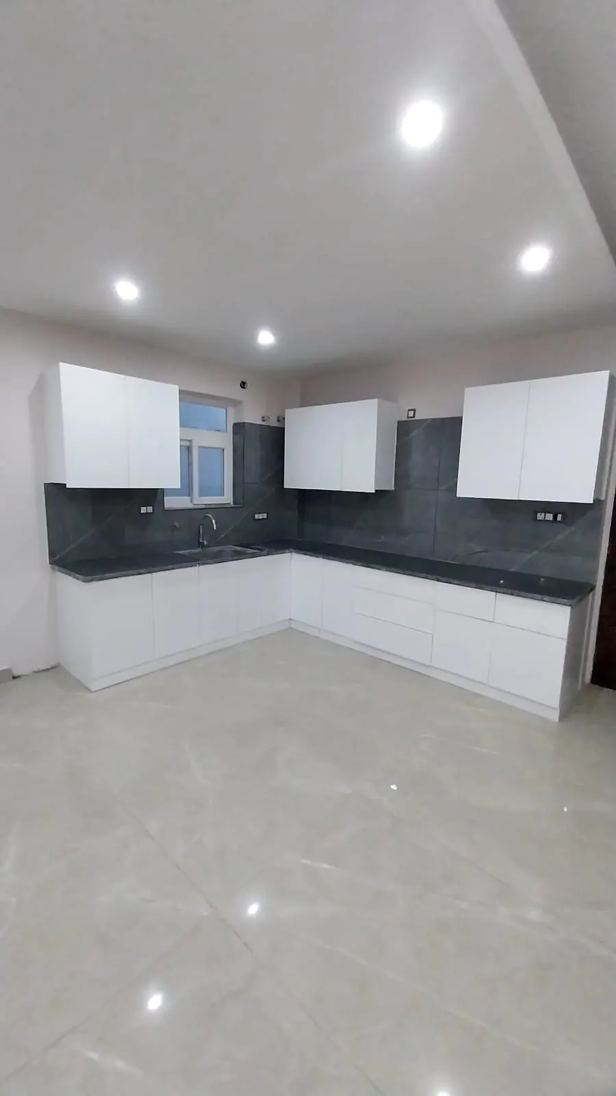 L-shaped modular kitchen with grey stone backsplash